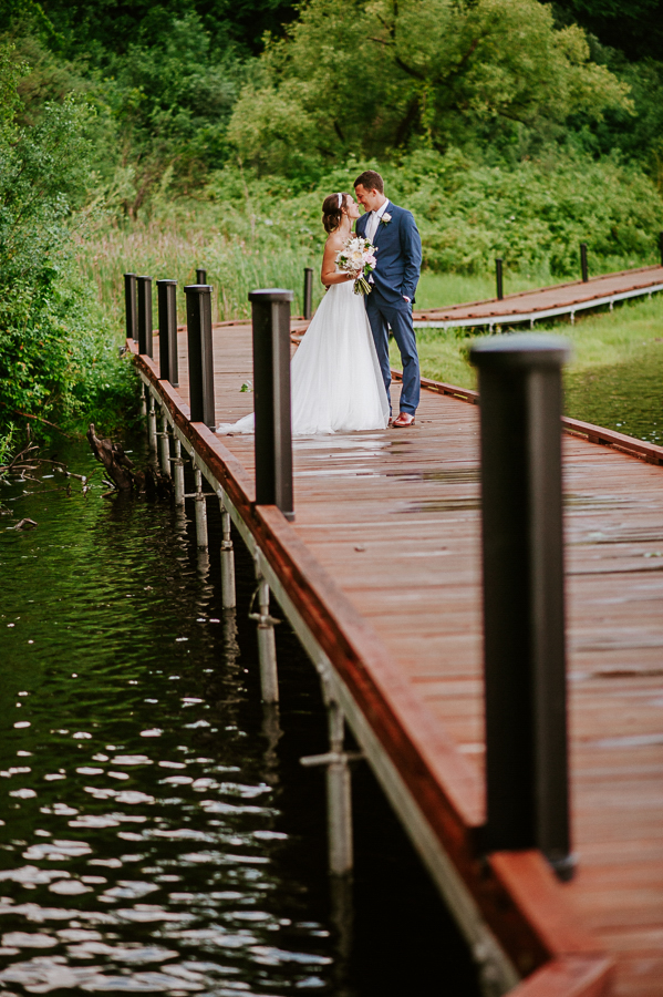 Bride and groom on boardwalk with pond