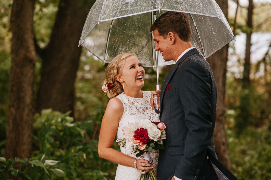 Bride and groom in rain with umbrella