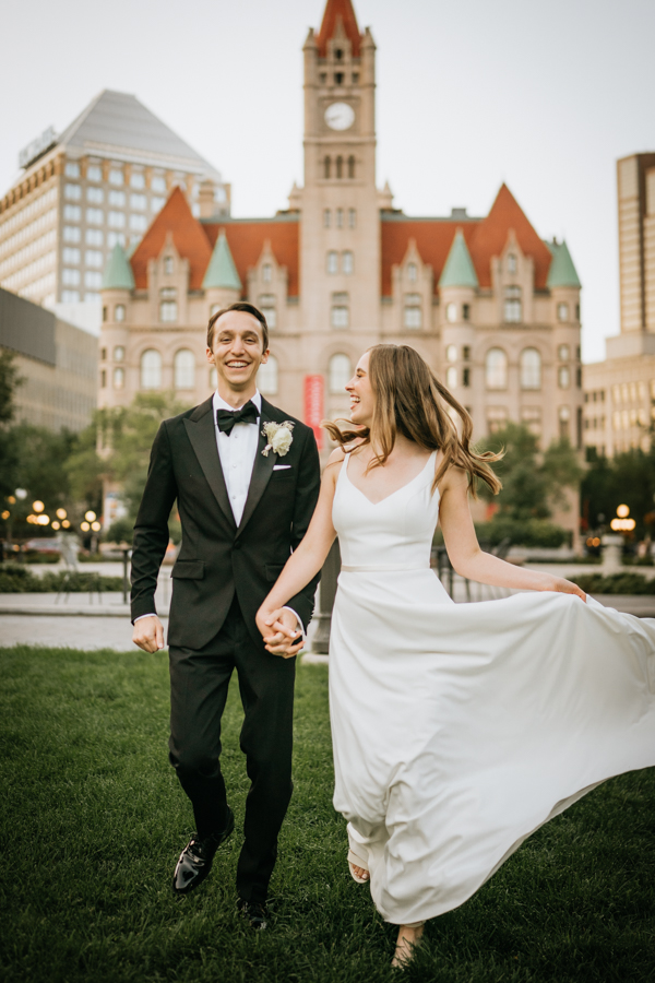 Bride and groom running with the Landmark Center in the background